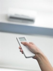 someone holding a remote and pointing it at a ductless unit.