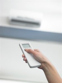 someone holding a remote and pointing it at a ductless unit.