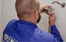 man in hoffmann uniform attaching a shower head