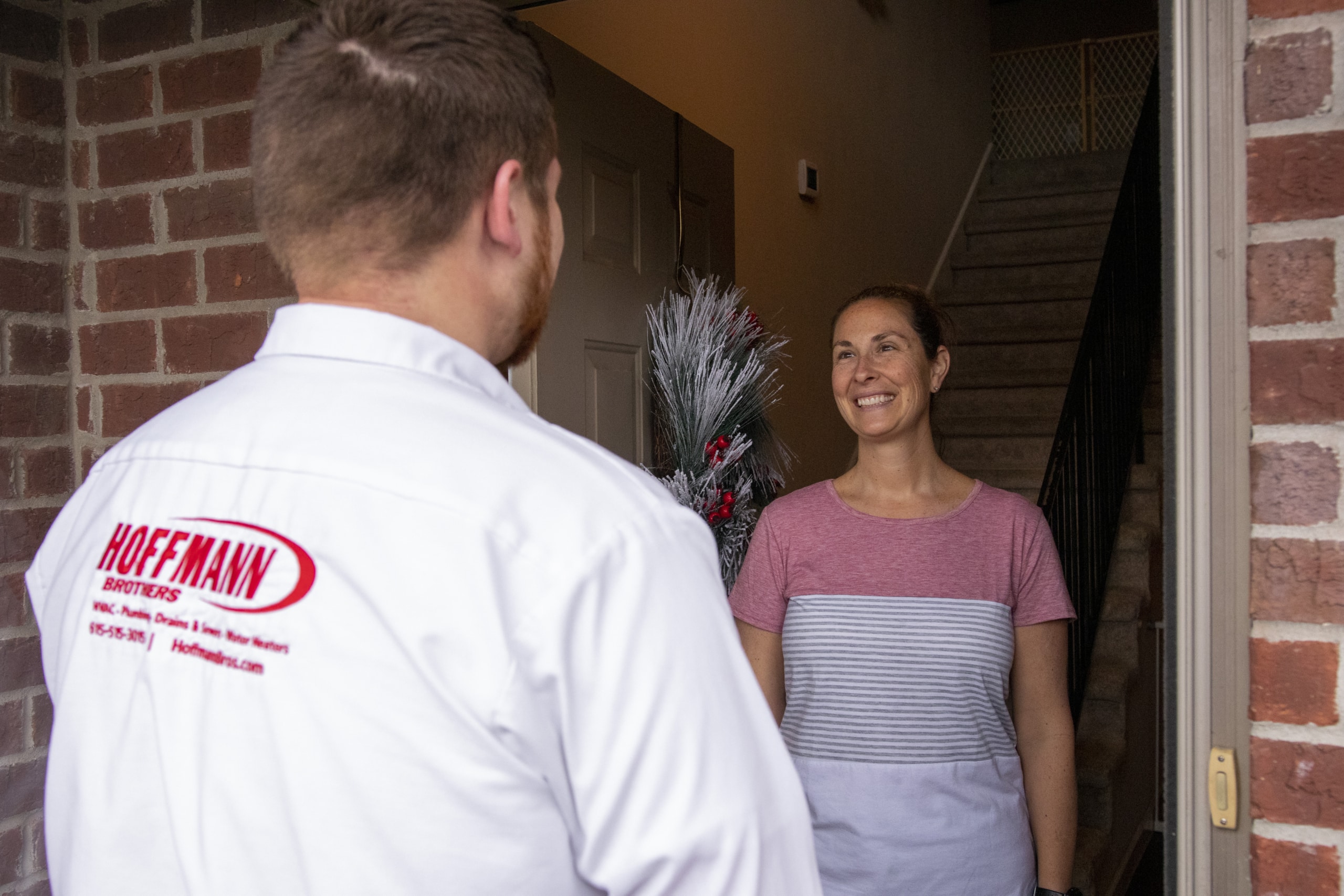 Woman wearing a pink and white striped shirt talking to Hoffmann Brothers technician before a Toilet Installation in Nashville, TN.