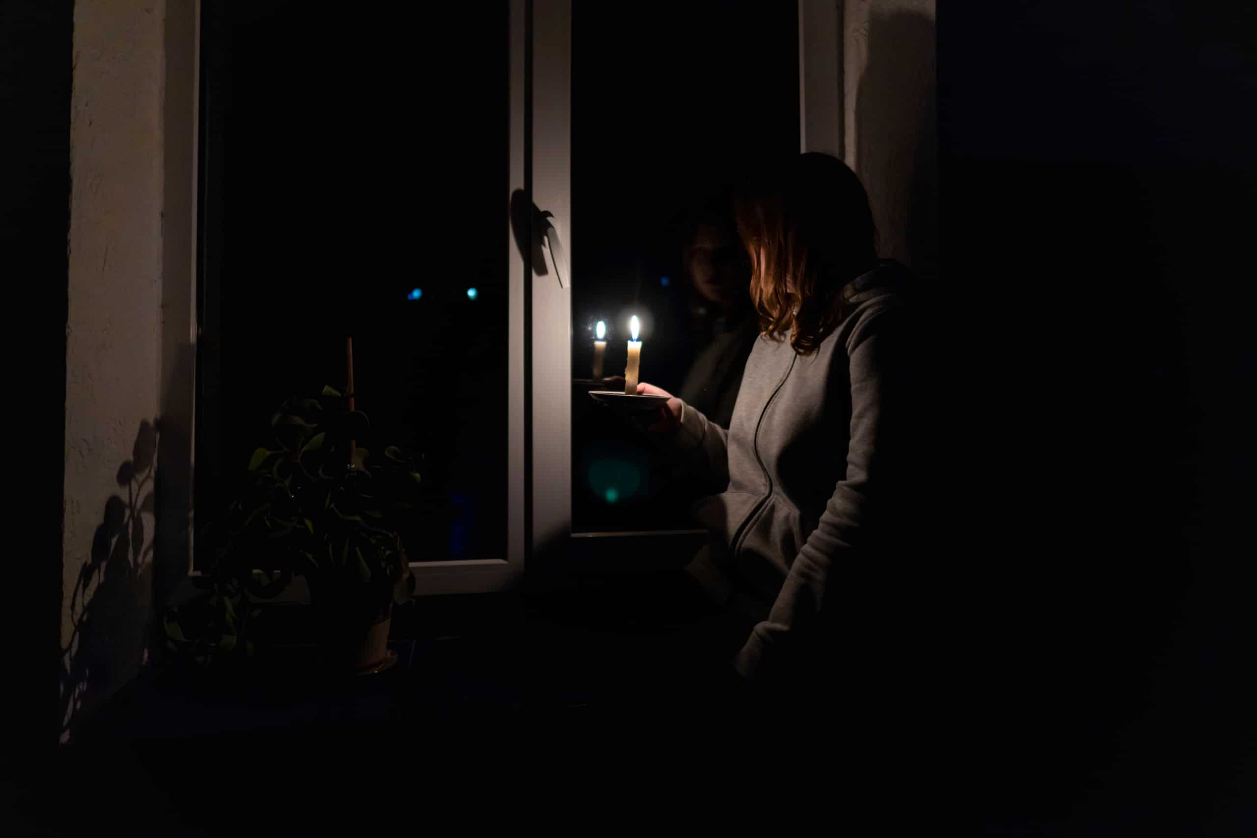 Woman with no Generator in Nashville holding a candle during a power outage