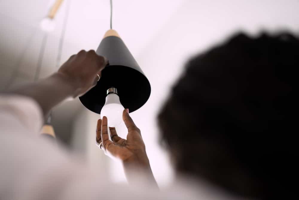 Person swapping out lightbulb for an LED bulb