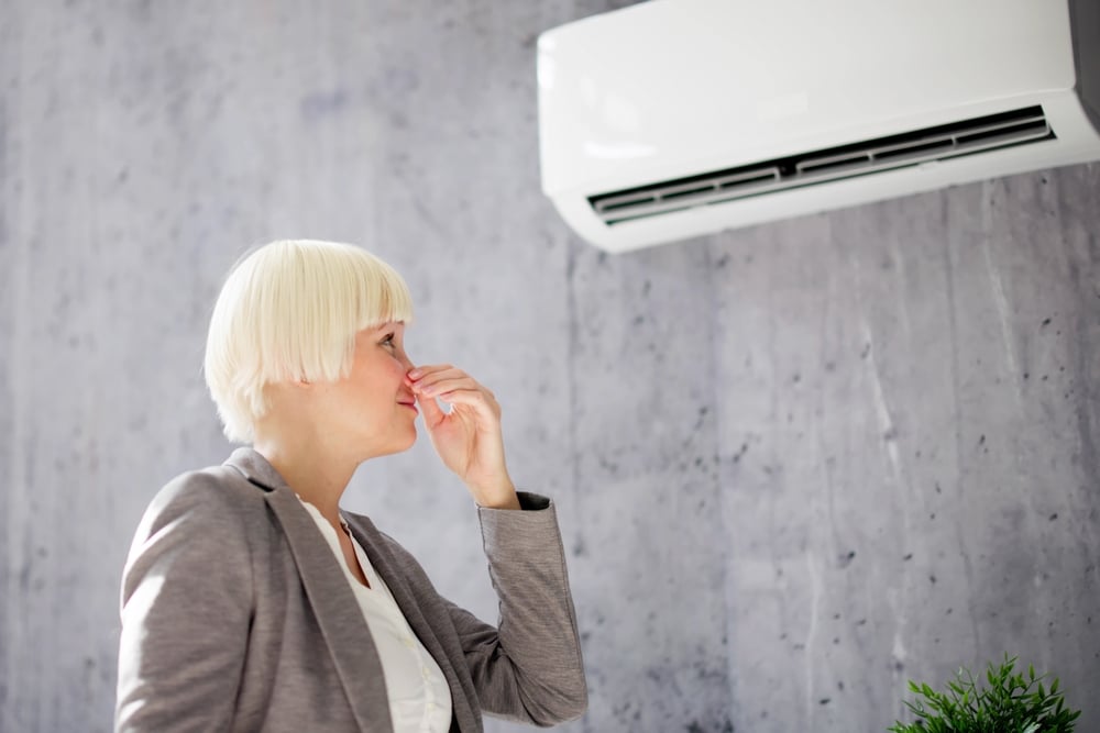 Person covering their nose from bad smell coming from air conditioner