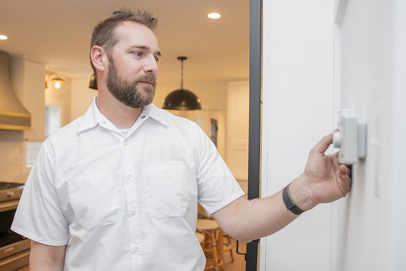 Photo of a technician testing an air conditioner, and setting it to the right settings