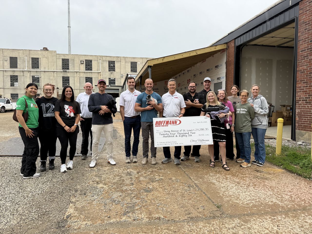 hoffmann brothers team standing with stray rescue team, holding puppies and presenting a giant check